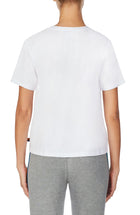 A lady wearing a white unisex T-Shirt with pride stripes.