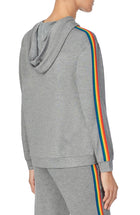 A lady wearing a grey long sleeve unisex reese hoodie with pride stripes in side.