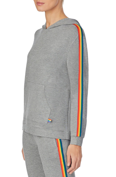 A lady wearing a grey long sleeve unisex reese hoodie with pride stripes in side.